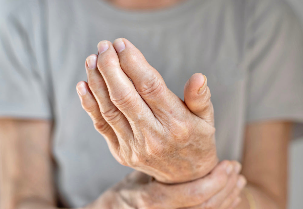 Nahaufnahme von Händen eines älteren Menschen, die das Handgelenk berühren, um Gelenkschmerzen zu zeigen.
