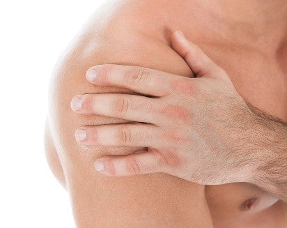 Nahaufnahme einer Person, die sanft ihre rechte Schulter mit der linken Hand berührt.